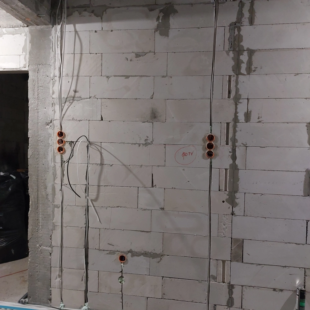 Ściana z białych bloczków z montażem instalacji elektrycznych, podtynkowe puszki i przewody