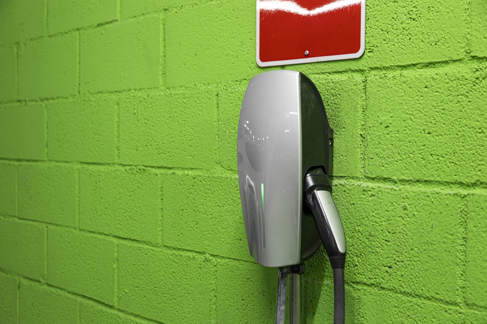 Stacja ładowania samochodów elektrycznych zamontowana na zielonej ścianie